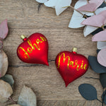 Cargar imagen en el visor de la galería, Set of 2 red heart-shaped glass Christmas balls with white text
